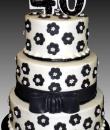 Black Flowers White Pearls 40th Birthday Cake. White buttercream iced, round, 3 tiers decorated with black flowers with white pearl centers, ribbon and bow. Everything on this cake is edible. (Serves 48-135 party slices) 